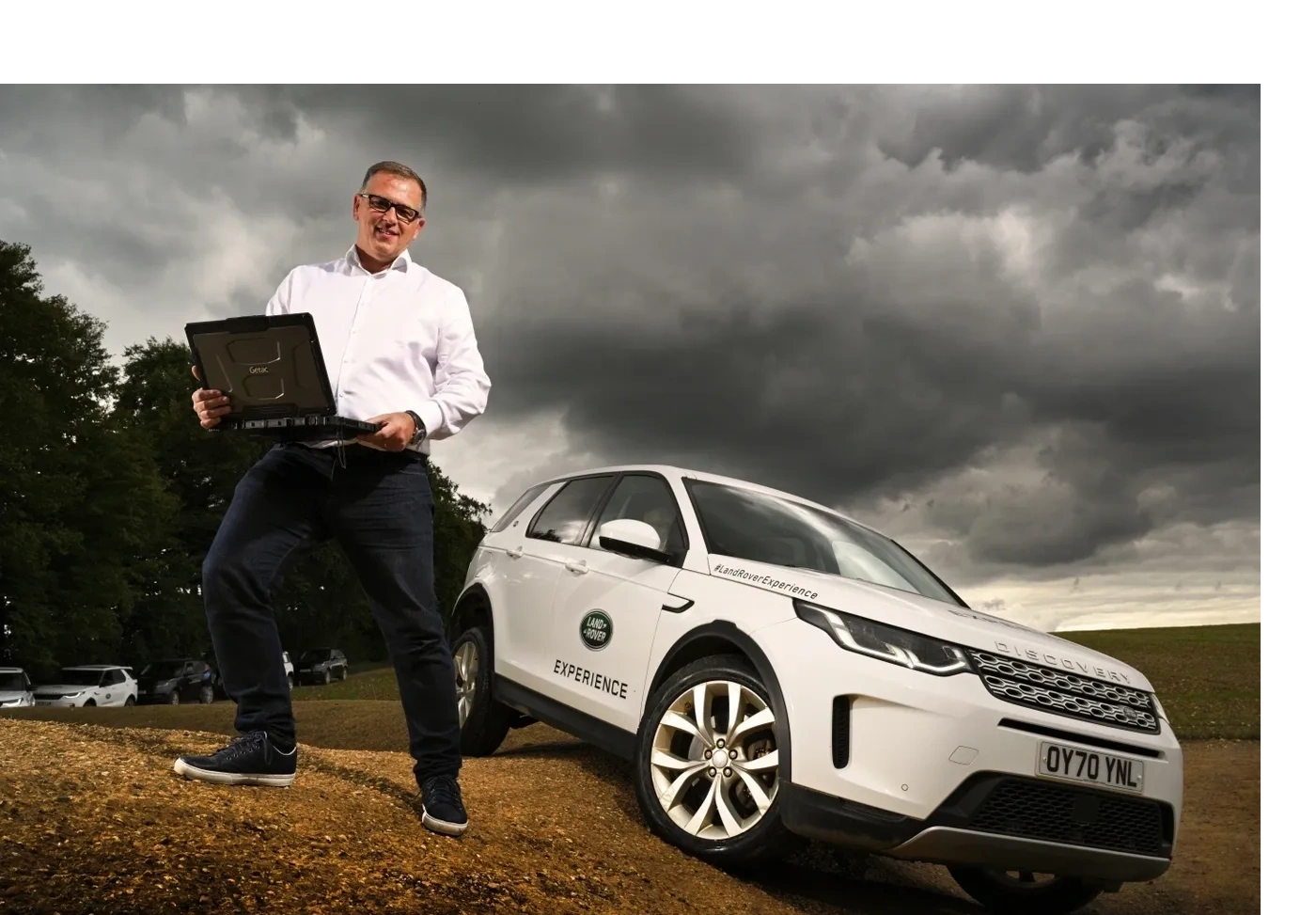 Professional man with laptop next to Land Rover